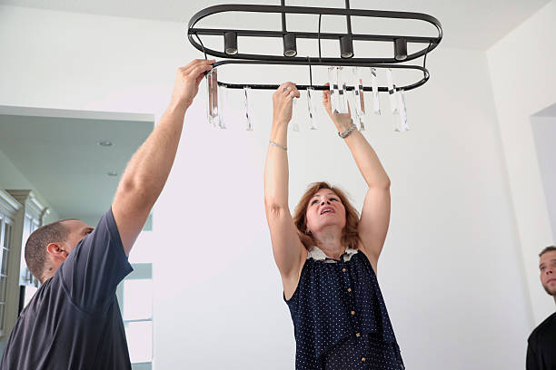 Professional stagers hanging a crystal light fixture